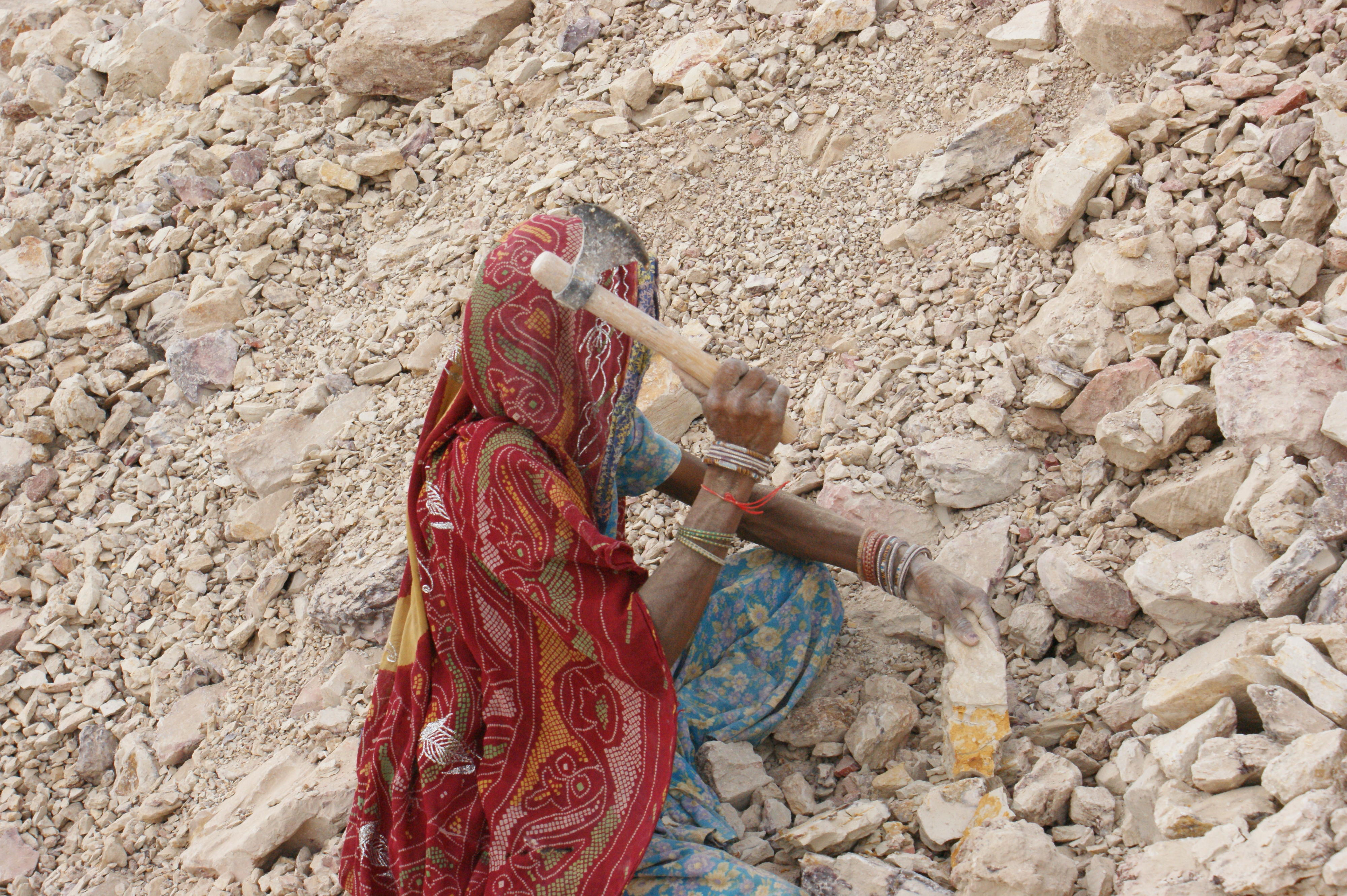 A woman worker breaks down stones at Gudah mine in Bikaner, Rajasthan